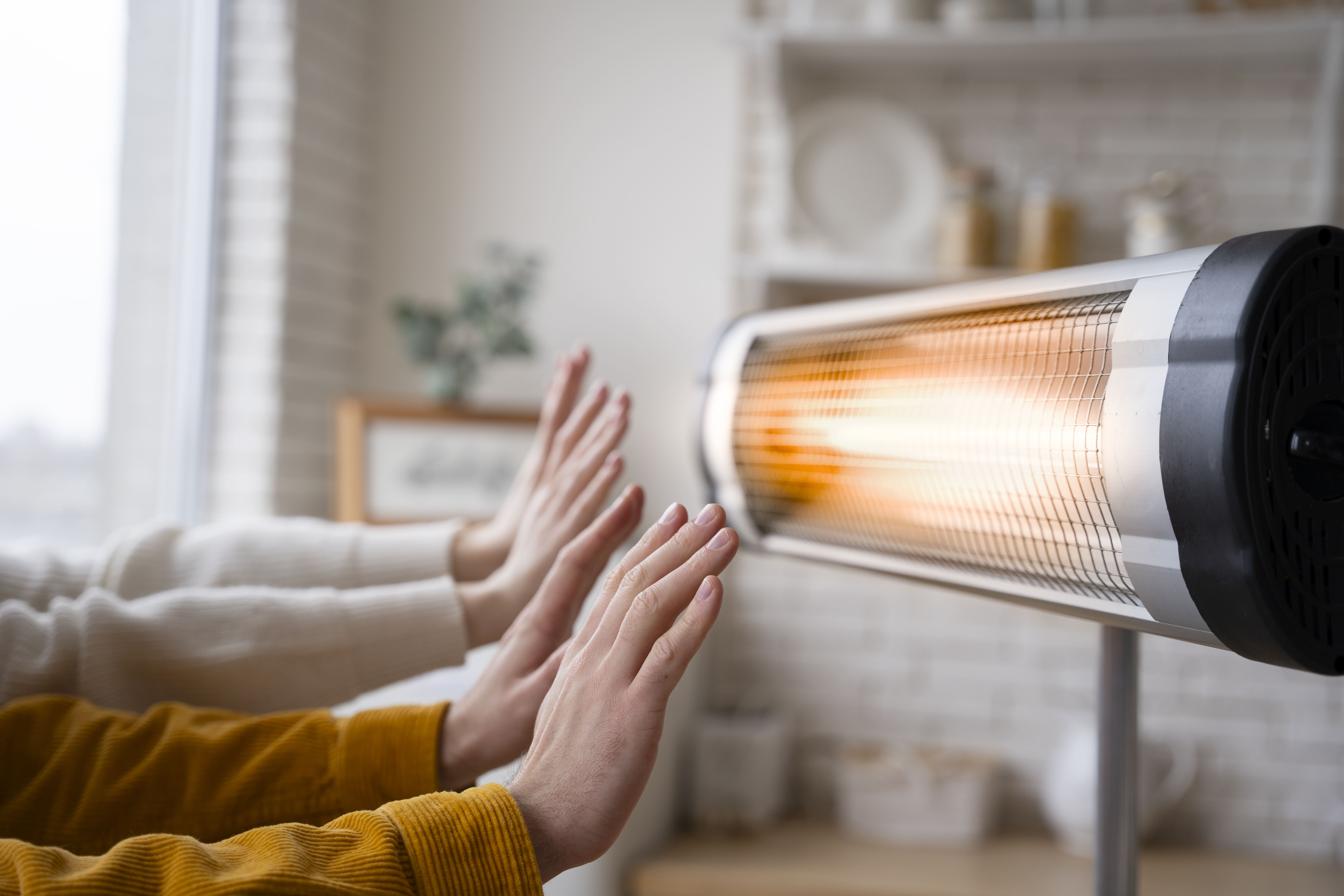 People warming up their hands near a heater